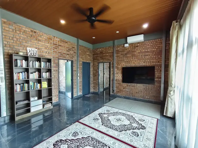 The upper-floor lounge with a bookshelf, rug and ceiling fan